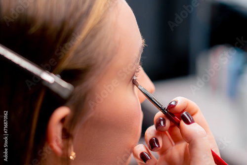 close-up of a make-up artist applying eyeshadow with a brush to a client's face in a beauty salon