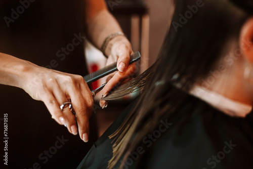 Female hairdresser cutting hair of brunette woman