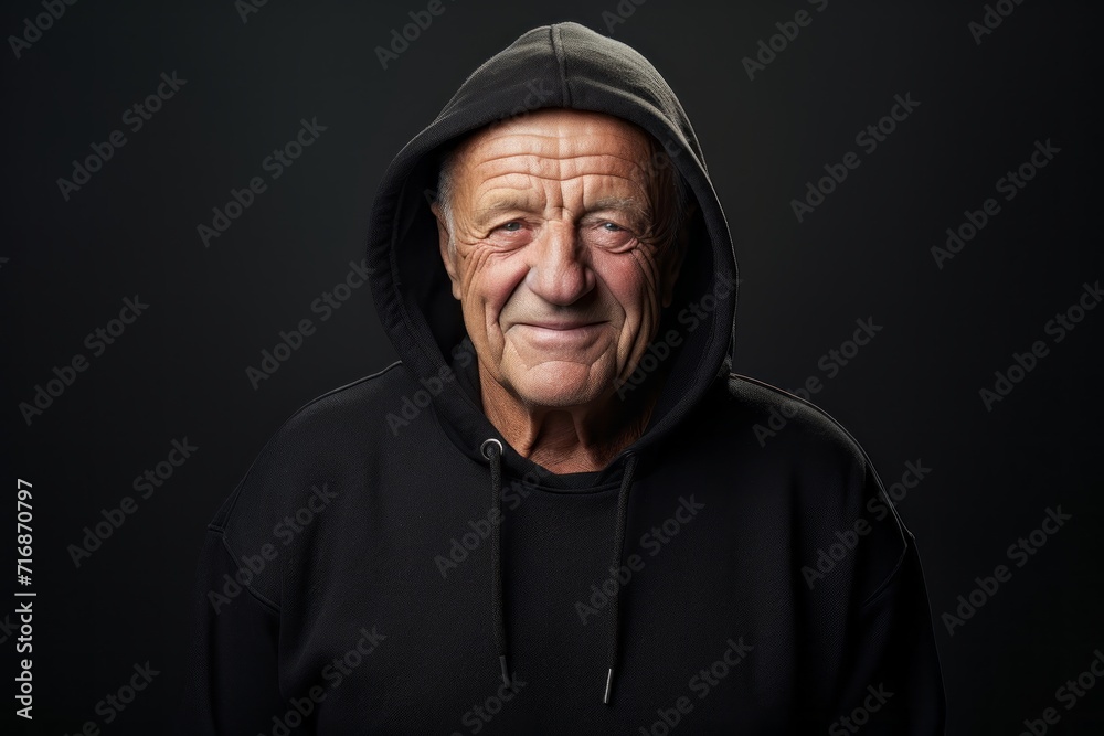 Fototapeta premium Portrait of a joyful man in his 70s wearing a zip-up fleece hoodie against a bare monochromatic room. AI Generation