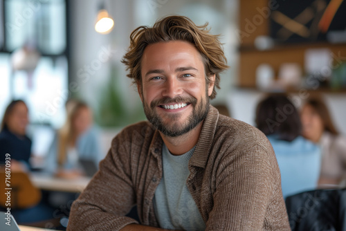 Portrait of handsome young man sitting in cafe and smiling at camera