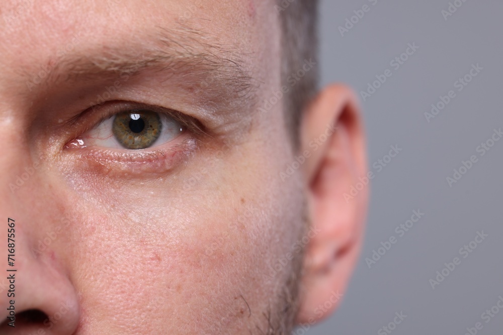 Closeup view of man with beautiful eyes on grey background, space for text