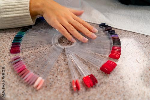 close-up of girl in beauty salon chooses the color of nail polish during a manicure a large palette