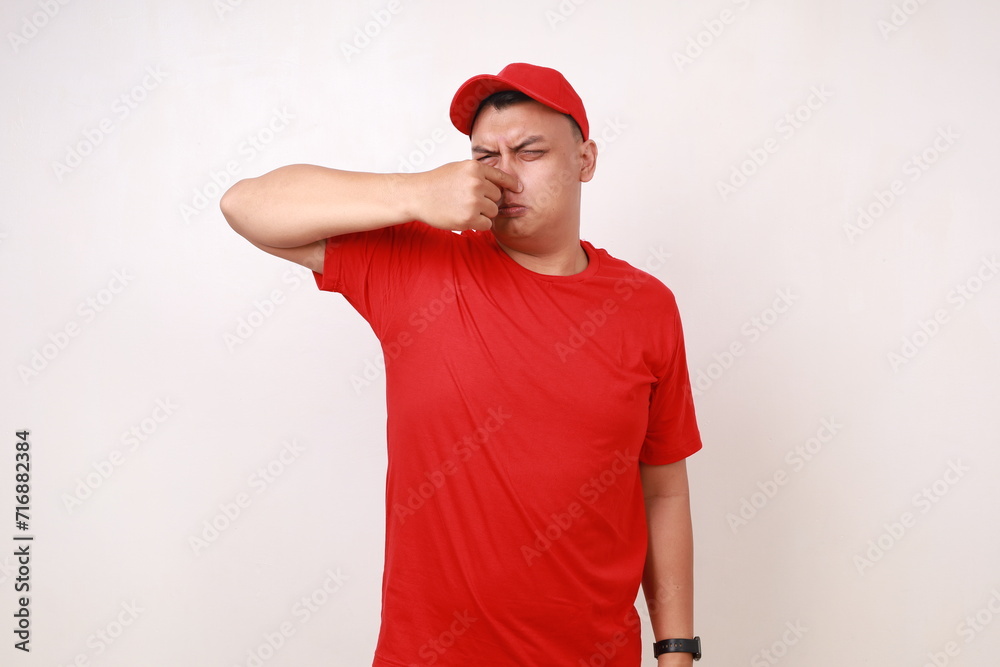 Funny young asian courier covering his nose, bad smell concept. Isolated on white Funny young asian courier covering his nose, bad smell concept. Isolated on white