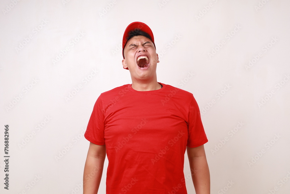 Frustrated young asian courier standing while screaming against white background