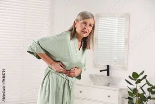 Menopause. Woman suffering from digestive problems in bathroom, space for text