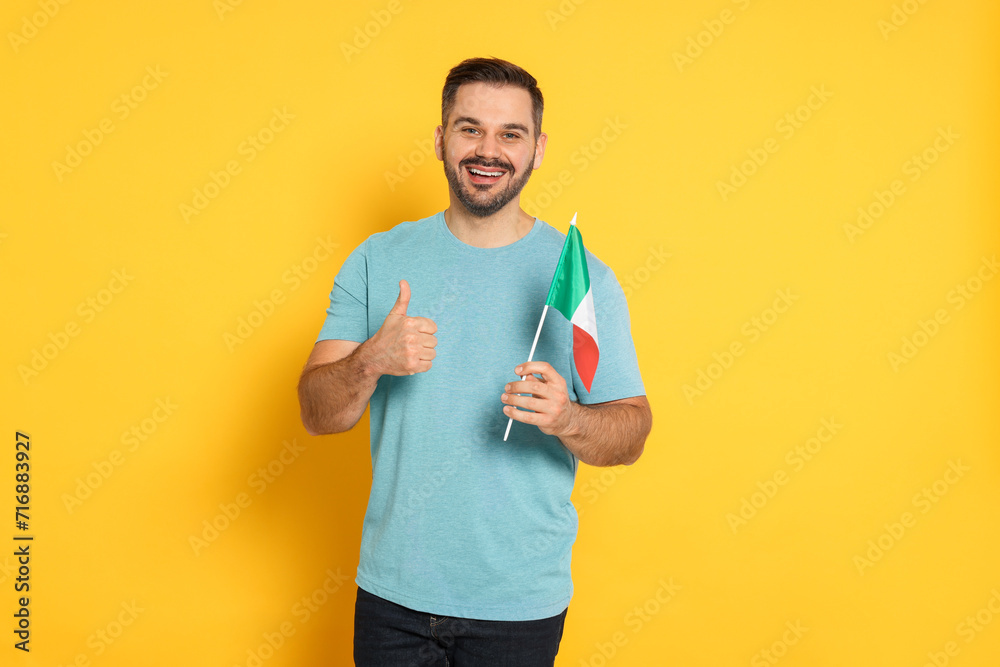 Man with flag of Italy showing thumb up on yellow background Man with flag of Italy showing thumb up on yellow background