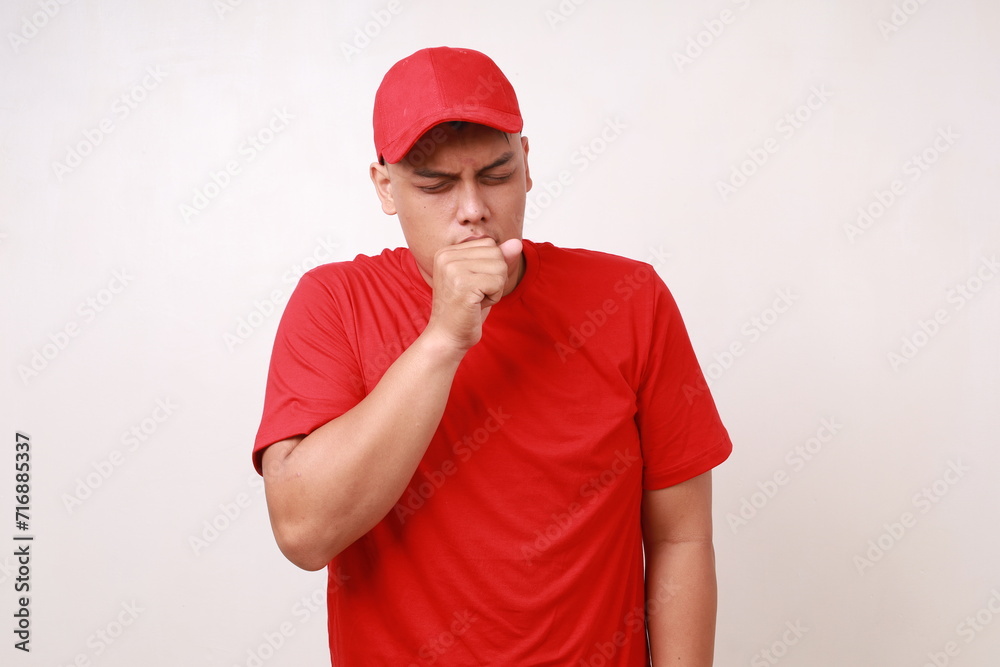 Asian delivery guy employee man in red covering his mouth while coughing Asian delivery guy employee man in red covering his mouth while coughing