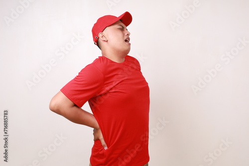 Asian delivery guy employee man in red having back pain. Isolated on white