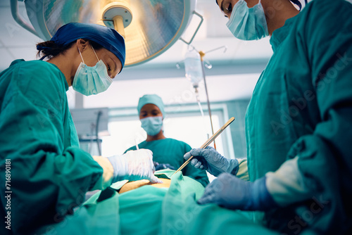 Female doctor performing surgery in operating room at medical clinic. photo