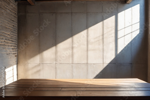 Empty copy space on a wooden tabletop against the cement loft wall with shadow and daylight indoors