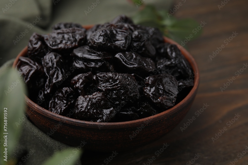 Sweet dried prunes in bowl on wooden table, closeup Sweet dried prunes in bowl on wooden table, closeup