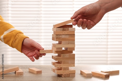 Obraz na plátně People playing Jenga tower at wooden table, closeup