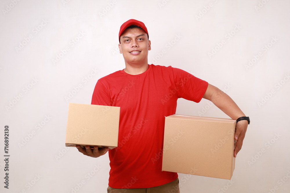 Happy Asian courier man in red holding cardboard box. Isolated on white Happy Asian courier man in red holding cardboard box. Isolated on white