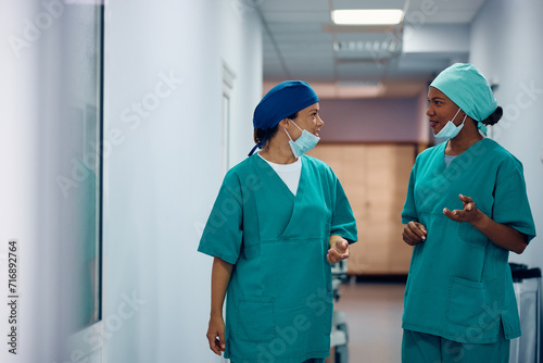 Multiracial female surgeons talking in hallway at hospital. photo