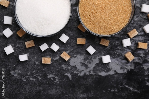 Different types of sugar in bowls on dark gray textured table, flat lay. Space for text photo