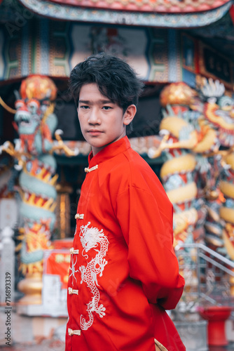 Portrait of young Asian man in traditional male Cheongsam Chinese dress on Chinese new year day isolated on Chinese shrine background, happy Chinese new year concept.Young man celebrating festival
