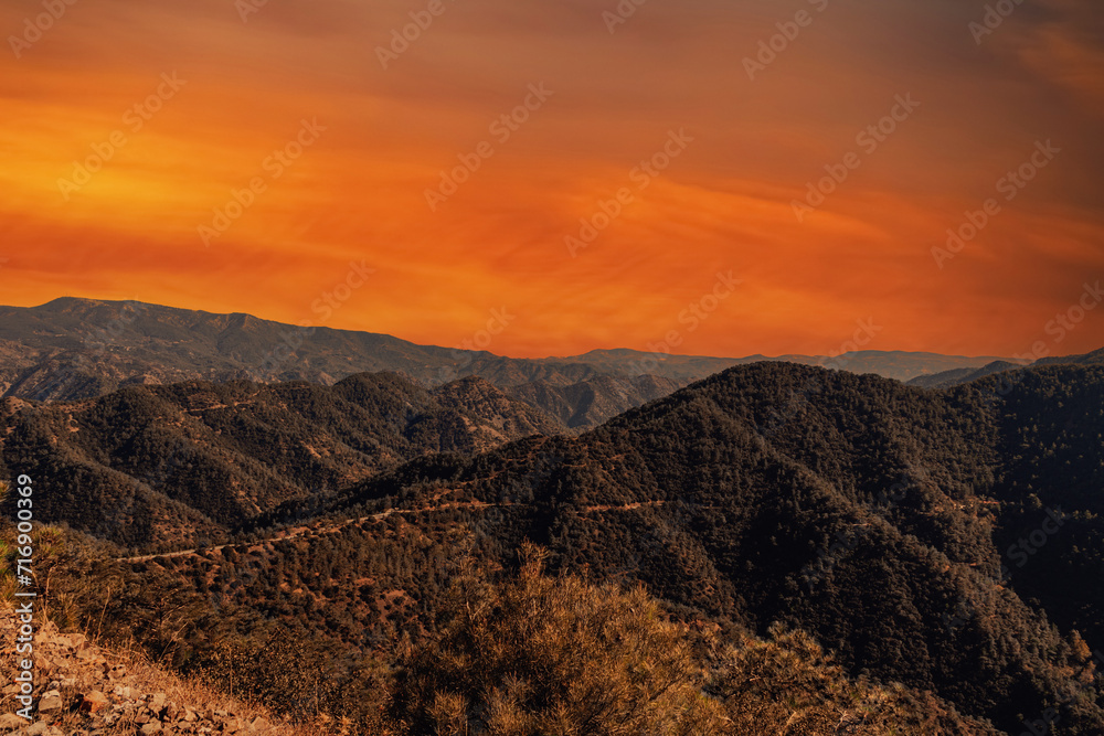 Mountain landscape at sunset. A view of the mountains with a bright orange sky in the background