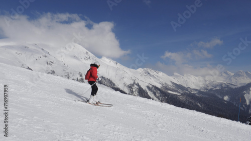 Active skier skiing down snowy slope in mountains at ski resort. Adrenaline is in blood from speed and breathtaking mountain scenery with snow capped summits and glaciers. Winter recreation and sports © dlogvin