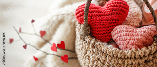 Hand-crafted red and pink crochet hearts in a woven basket with heart-shaped twigs, creating a cozy and warm atmosphere, ideal for DIY craft tutorials, Valentine's Day gift ideas, or home decor photo
