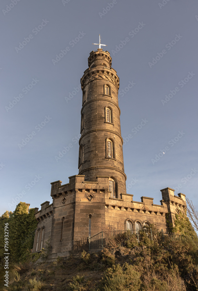 Bottom-up view of Nelson's Monument with a bright blue sky in the background. Architecture design of Tower situated on Calton Hill at Edinburgh, Scotland, Space for text, Selective focus.