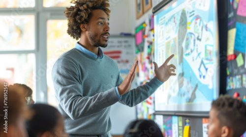 Teacher is actively engaging with his students in a classroom setting, with educational materials visible on the whiteboard behind him. photo