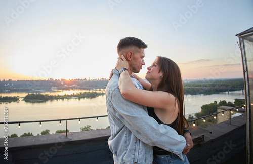A young couple kisses and embraces during a romantic rooftop date