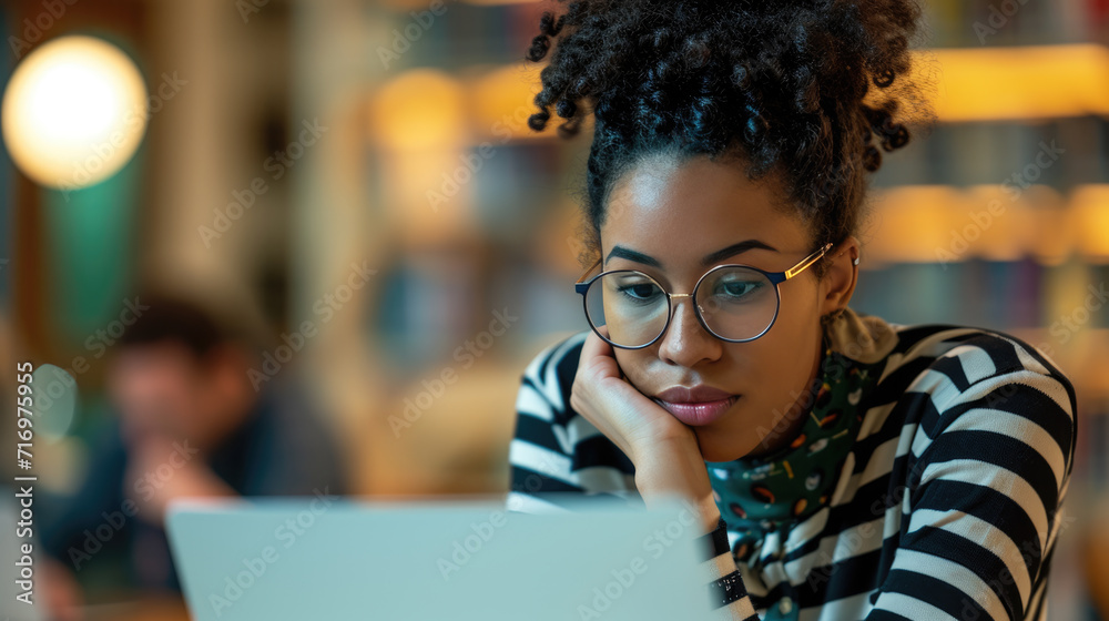 Young woman is focused on working on her laptop in a modern office Young woman is focused on working on her laptop in a modern office