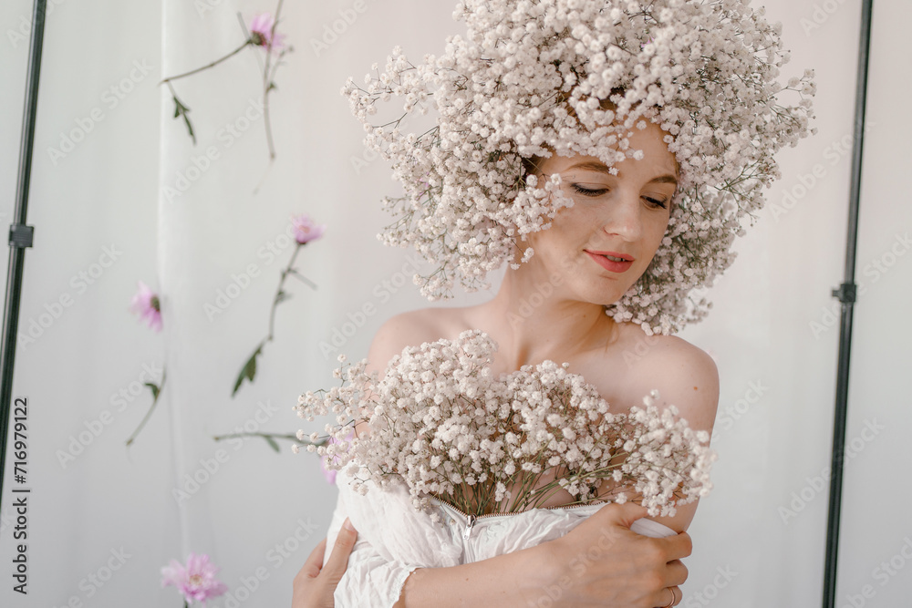 Portrait of sensual blond woman with flowers. Beautiful girl with flowers in her hair. Summer Beauty. Art in a contemporary style. A gypsophila wreath on a white background. Perfume, cosmetics concept Portrait of sensual blond woman with flowers. Beautiful girl with flowers in her hair. Summer Beauty. Art in a contemporary style. A gypsophila wreath on a white background. Perfume, cosmetics concept