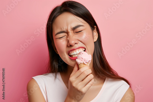 Asian Woman In Pain From Sensitive Teeth Touches Cheek While Eating Ice Cream