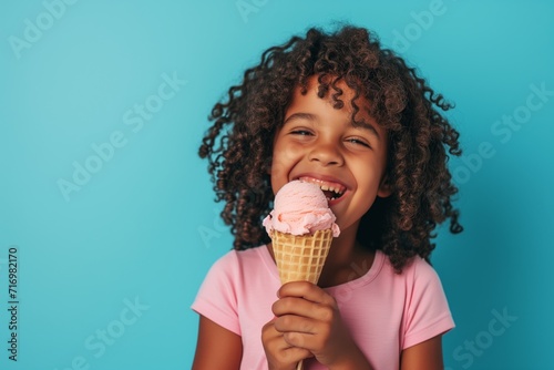 Joyful African American Child Indulges In Ice Cream In Waffle Cone  Set Against Vibrant Blue Background