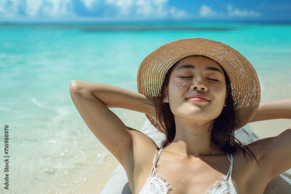 Radiant Asian Woman Blissfully Sunbathes On Caribbean Beach, Embracing Summer Relaxation
