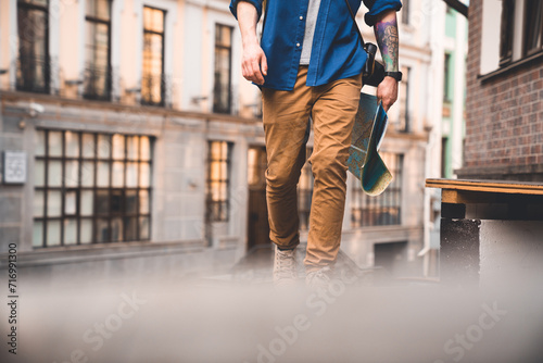 Mid section shot of man walking on downtown district streets with map in hands. Male tourist traveler exploring the old city finding direction route way in summer photo