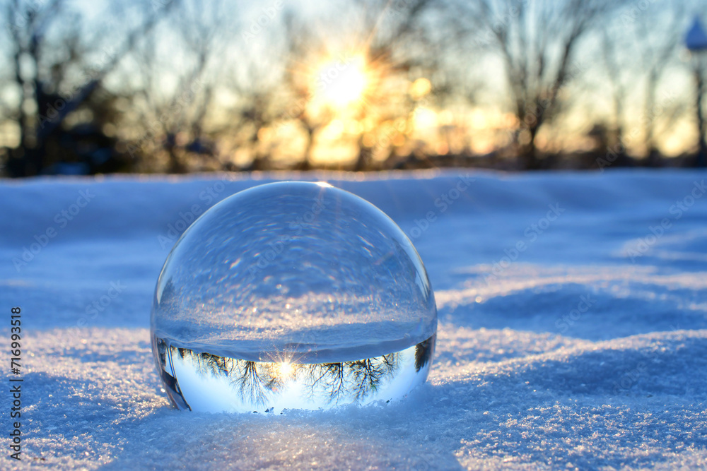 Winter sunrise with snow as seen in a lens ball with starburst sun. Concept for environment background Winter sunrise with snow as seen in a lens ball with starburst sun. Concept for environment background