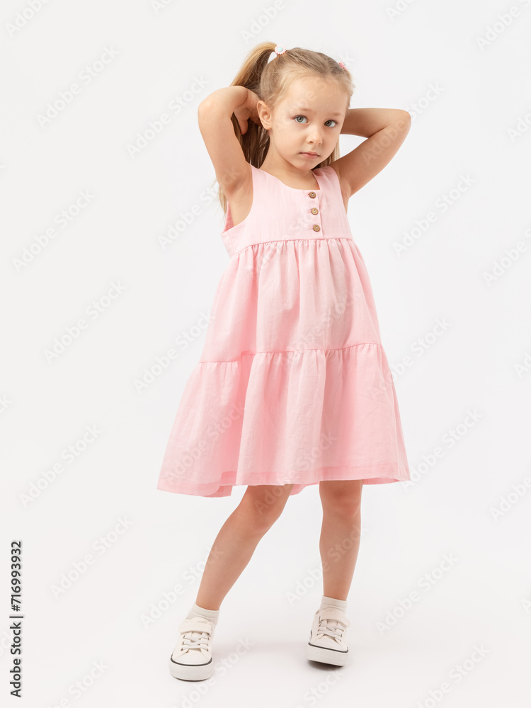 Beautiful girl model in a pink dress posing, straightening her hair on a white background. Looking into the camera. Beautiful girl model in a pink dress posing, straightening her hair on a white background. Looking into the camera.