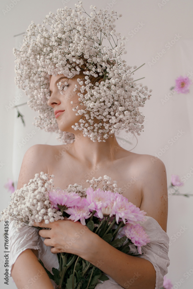 Portrait of sensual blond woman with flowers. Beautiful girl with flowers in her hair. Summer Beauty. Art in a contemporary style. A gypsophila wreath on a white background. Perfume, cosmetics concept Portrait of sensual blond woman with flowers. Beautiful girl with flowers in her hair. Summer Beauty. Art in a contemporary style. A gypsophila wreath on a white background. Perfume, cosmetics concept
