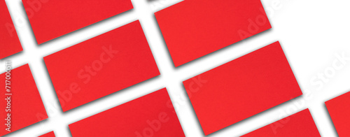 Mockup of horizontal red business cards stacks arranged in rows at white textured paper background. Banner.