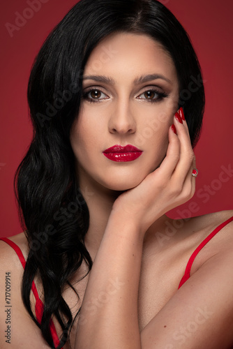 Beauty studio portrait of young beautiful woman against red background.