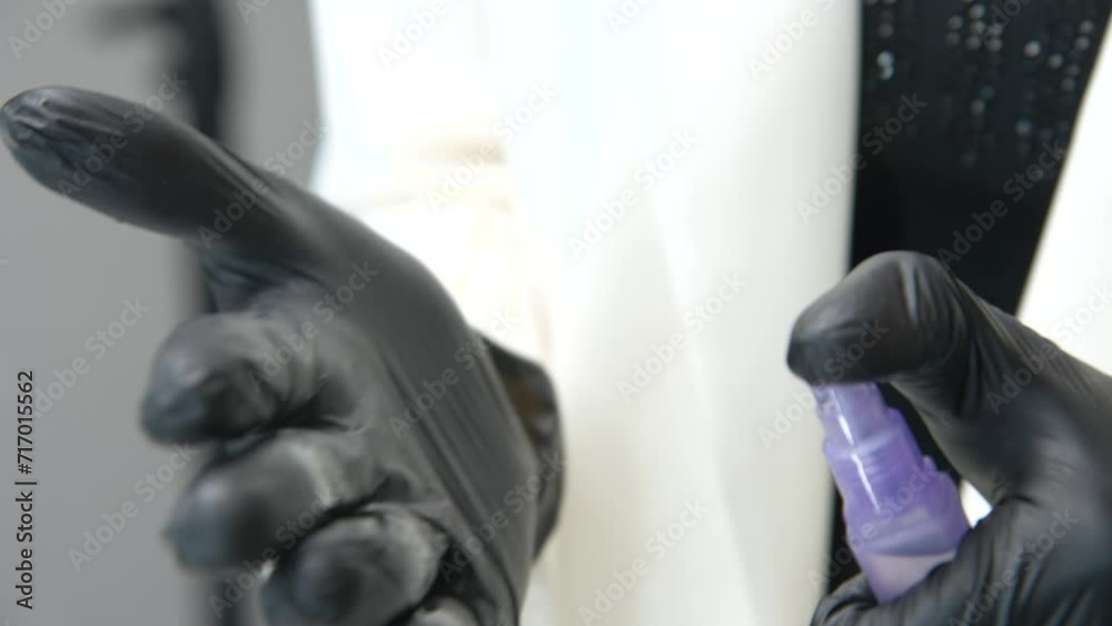 Side view of cosmetic disinfectant spray and hands in black gloves with cotton pad, close-up of hygiene standards in beauty salon Side view of cosmetic disinfectant spray and hands in black gloves with cotton pad, close-up of hygiene standards in beauty salon