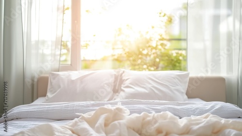 A bed in focus with pillows in a warm morning tone. Bed with white sheets and pillows with a blurred external background.