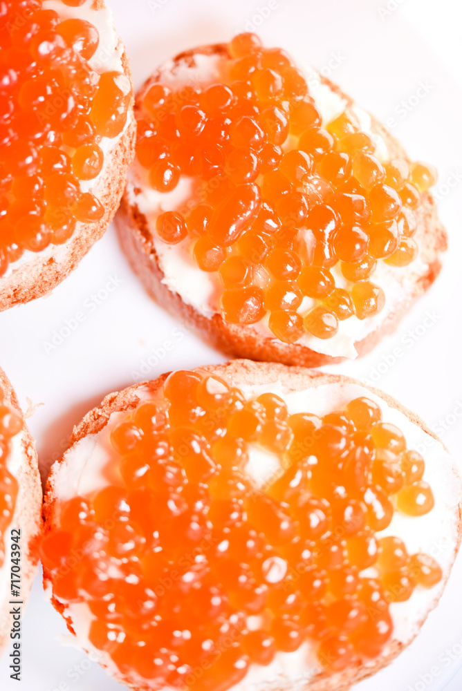 Red salmon caviar on bread and butter. A sandwich with caviar and butter on a plate.