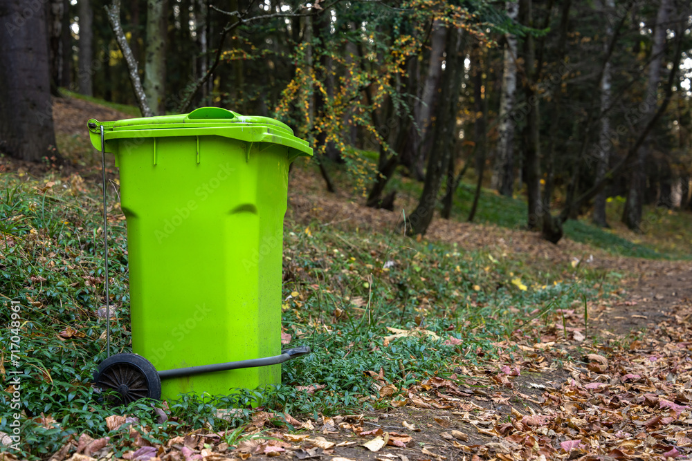 Big green trash can in the forest, concept of environmental protection Big green trash can in the forest, concept of environmental protection