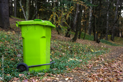 Big green trash can in the forest, concept of environmental protection