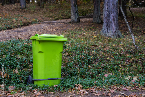 Big green trash can in the forest, concept of environmental protection