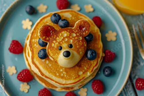 Funny food for kids. Bear shaped pancakes with berries on blue wooden table, top view