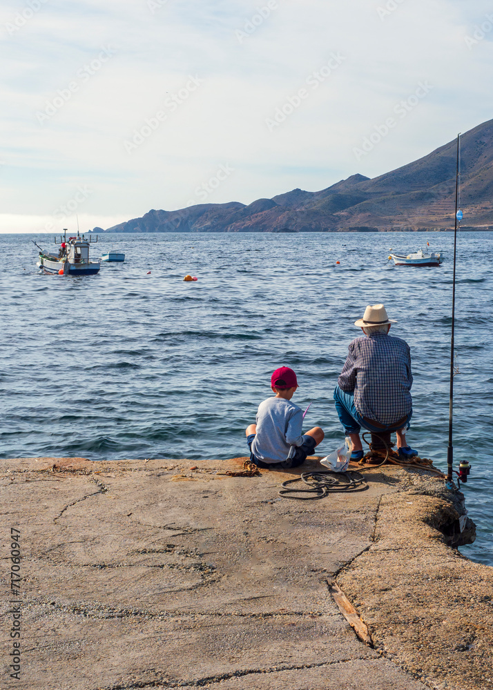 Abuelo y nieto pescando en el muelle de la Isleta del Moro en Almería, España