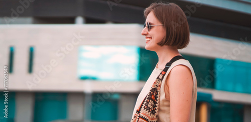 A girl in sunglasses with a smiley face walks around the city.