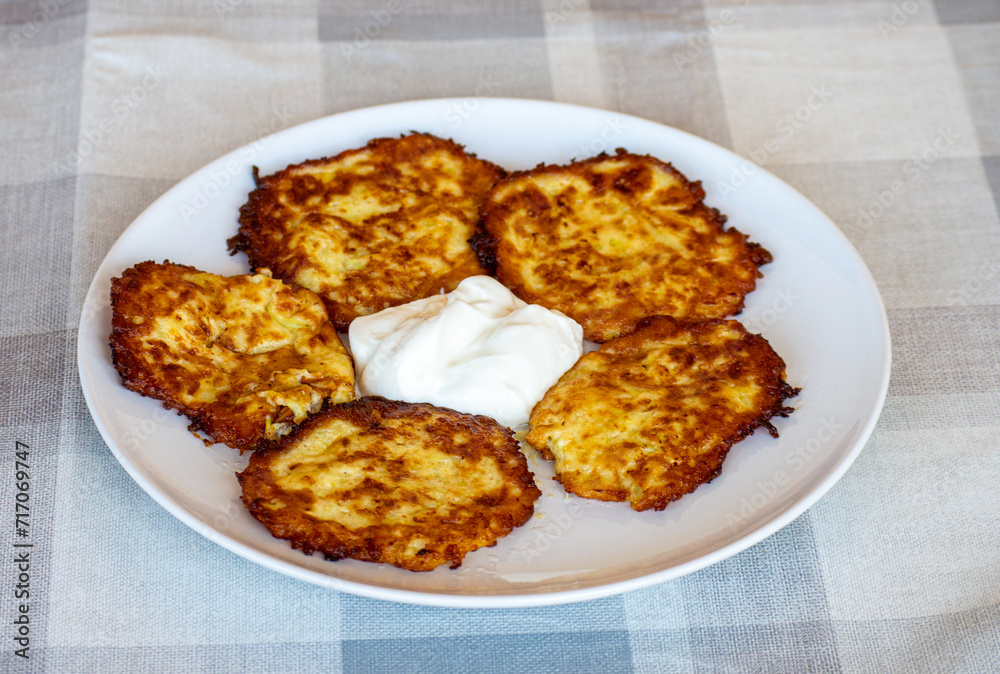 Potato pancakes on a plate with sour cream, Ukrainian national dish Potato pancakes on a plate with sour cream, Ukrainian national dish