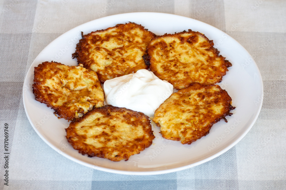 Potato pancakes on a plate with sour cream, Ukrainian national dish Potato pancakes on a plate with sour cream, Ukrainian national dish