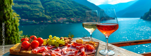 Sausages, cheeses and wine on the shore of a mountain lake. Selective focus.
