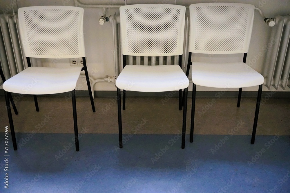 Obraz premium Innenausstattung von Warteraum mit drei weißen Stühlen vor Heizkörper in Krankenhaus